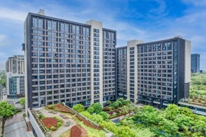 A high-rise building with multiple floors, surrounded by greenery and other buildings. - Zhoushan Xingning Holiday Hotel (Zhoushan)