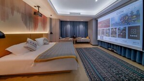 Een moderne hotelkamer met een groot bed, een zithoek met uitzicht en een scherm met content.