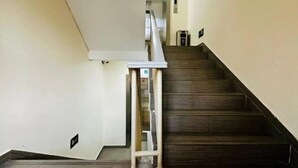 Una escalera con barandilla, un rellano con una puerta y un aplique de pared.