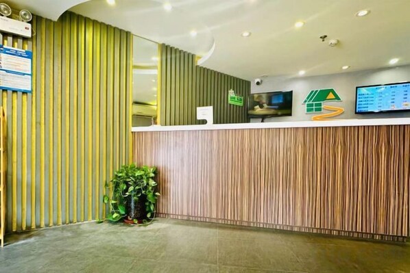 A reception area with a wooden reception desk, a green vertical panel, and a digital display. - Shanghai Zhong'an Hotel (Shanghai Railway Station Xizang North Road Subway Station) (Shanghai)