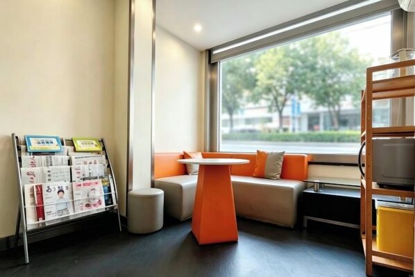 Un interior moderno con una zona de estar junto a una ventana, una mesita y un mueble para revistas.