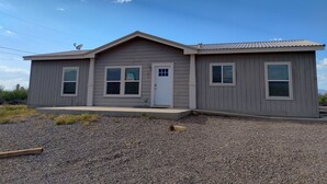 A single-story building with a gabled roof, a front door, and two windows on the side. - Gila Valley Escape (Central)