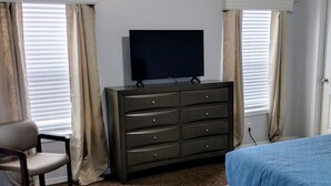 A bedroom with a bed, a dresser, a chair, and a television. - Gila Valley Escape (Central)
