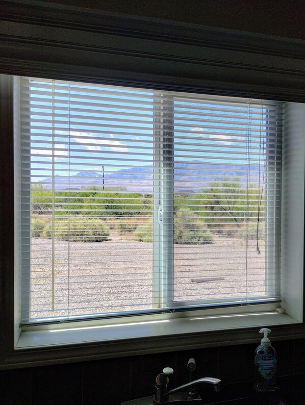 A bathroom with a window overlooking a desert landscape.