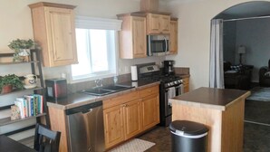 A modern kitchen with wooden cabinets, stainless steel appliances, and a central island. - Gila Valley Escape (Central)
