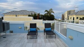 Eine Dachterrasse mit zwei Liegestühlen und einer Brüstung.