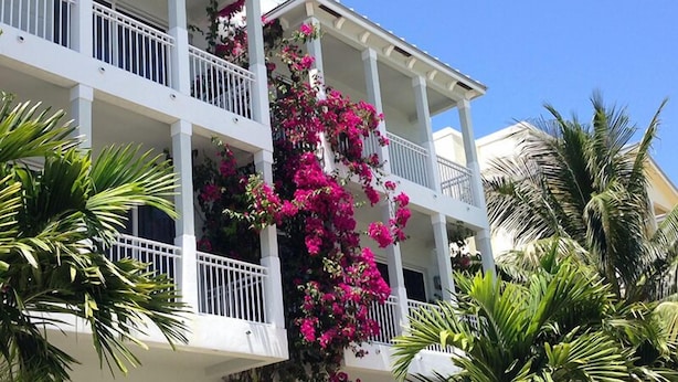 Ein mehrstöckiges Gebäude mit Balkonen, die mit leuchtend rosa Bougainvillea bepflanzt sind.
