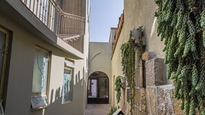 A narrow alleyway with a building on the left featuring a balcony with metal railings and a door with a glass panel. - Hotel Casa Aliz (San Miguel de Allende)