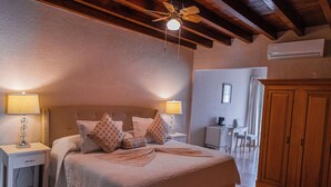 A bedroom with a large bed, two bedside tables with lamps, a wooden wardrobe, and a ceiling fan. - Hotel Casa Aliz (San Miguel de Allende)