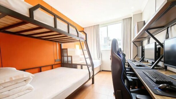 A bunk bed with a desk and computer setup, a window with curtains, and a city view. - Shanghai Wuzhou Esports Hotel (Shanghai)