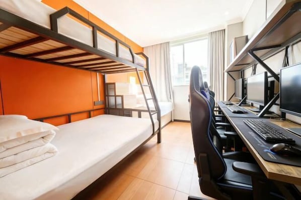 A bunk bed with a desk and computer setup, a window with curtains, and a city view.