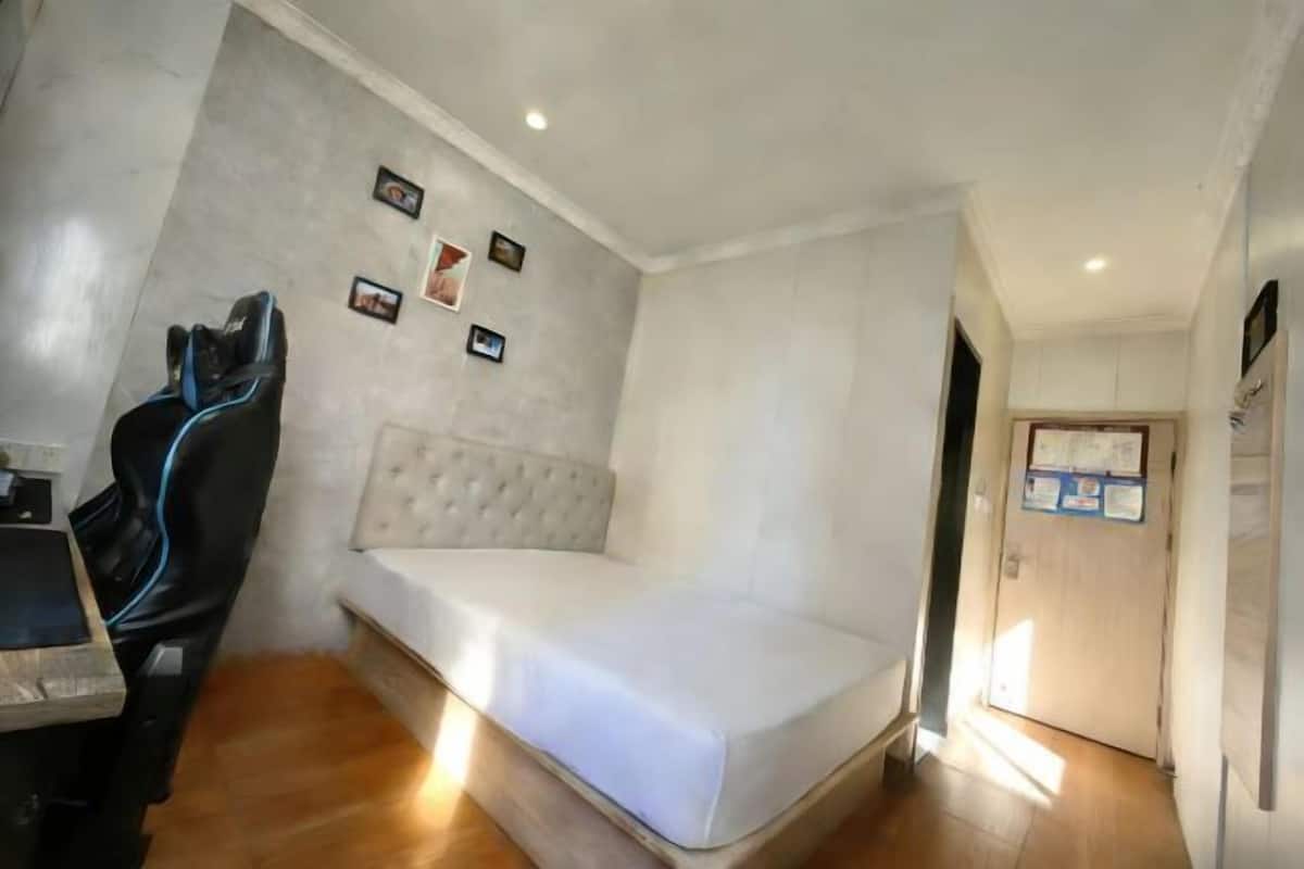 Quarto com uma cama, uma escrivaninha com cadeira e uma porta.