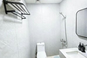 A bathroom with a white toilet, a shower, a sink, and a mirror.