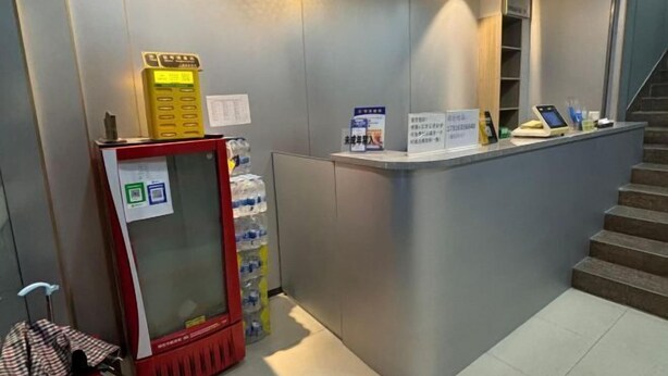 A reception desk with a vending machine, water dispenser, and a staircase. - Shanghai Wuzhou Esports Hotel (Shanghai)