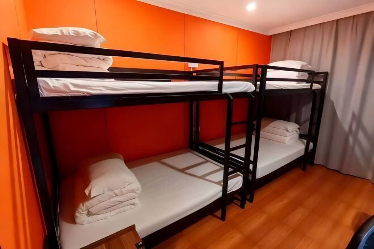 Quarto com beliche, paredes alaranjadas e piso de madeira.