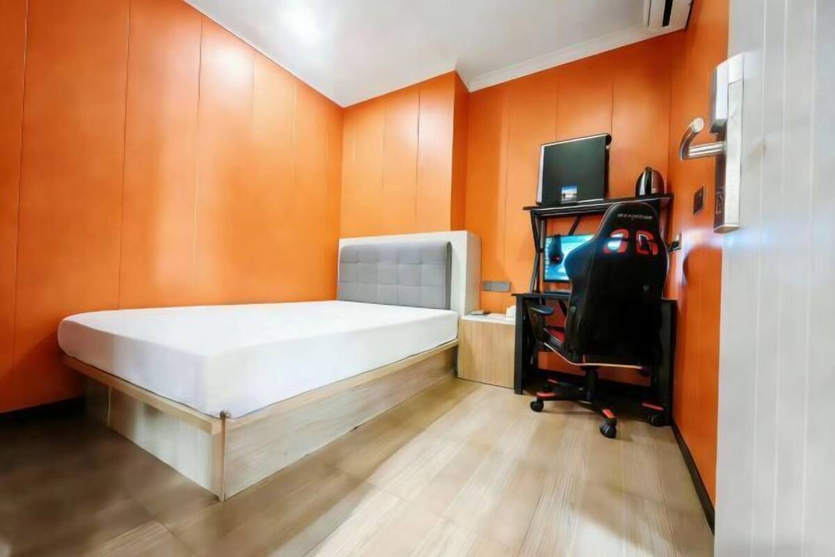 Quarto com uma cama, uma escrivaninha com computador e ar condicionado.