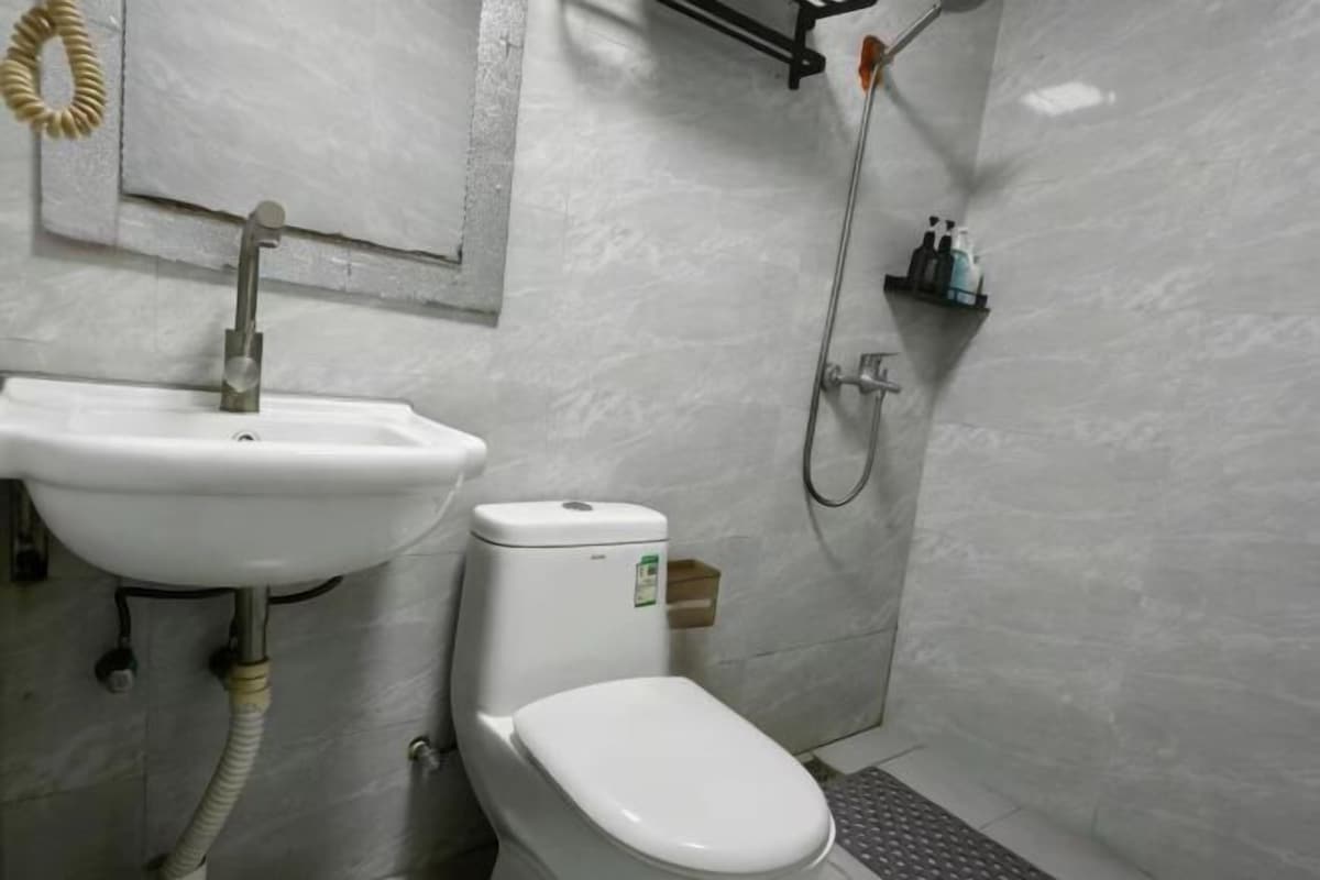Une salle de bain avec un lavabo, des toilettes et une douche, le tout de couleur blanche.