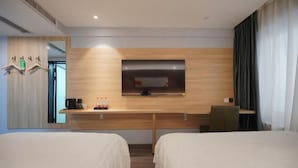 Una habitación de hotel con dos camas, un escritorio, un espejo y un televisor de pantalla plana.