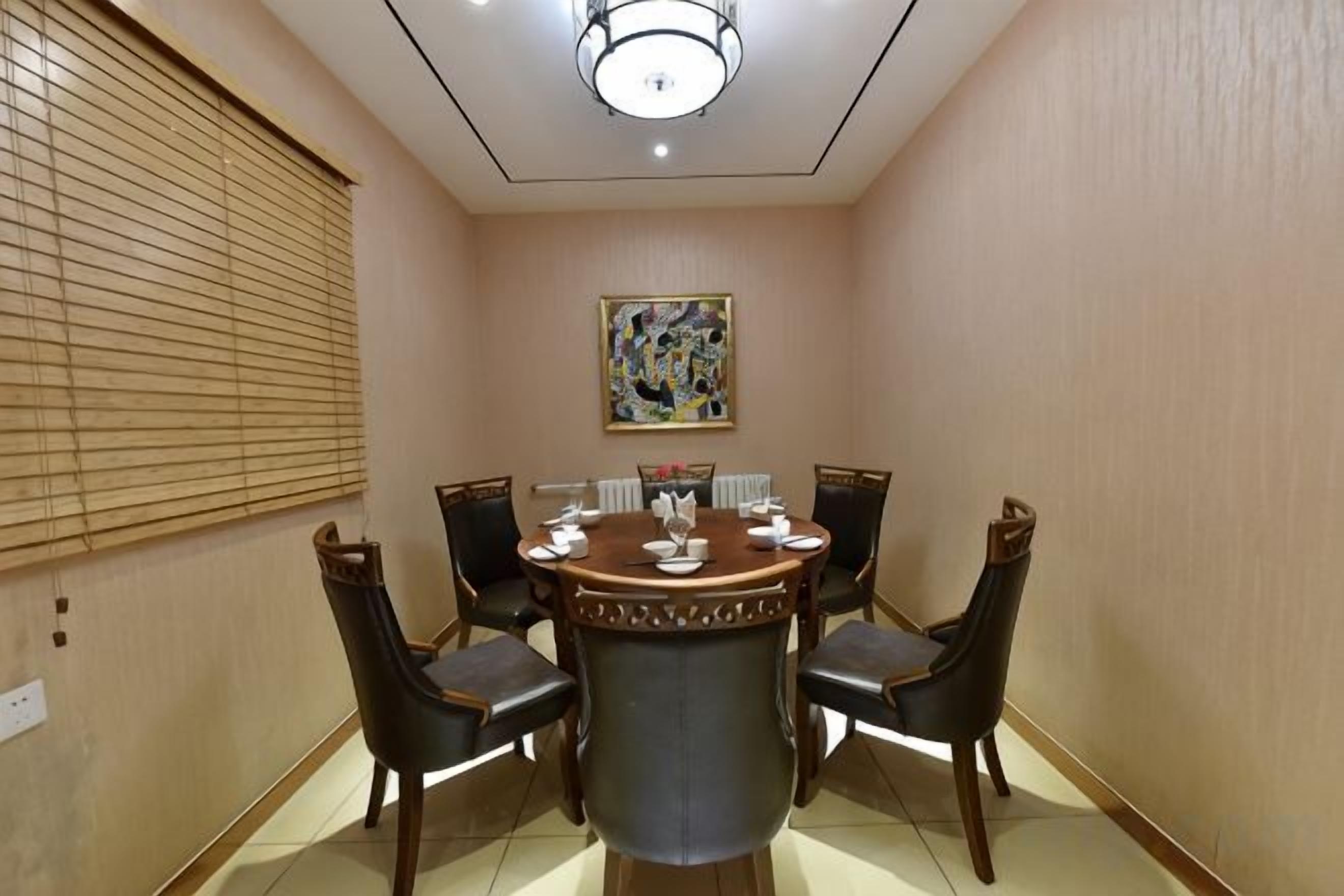 A conference room with a round table, six chairs, and a painting on the wall.