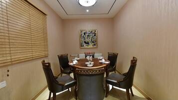 A conference room with a round table, six chairs, and a painting on the wall.