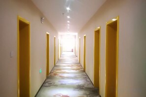A hotel corridor with doors on both sides, a patterned carpet, and a light source at the end. - Beijing Dongdan Hotel (Beijing)