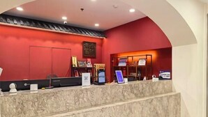 Zona de recepción con mostrador de mármol, paredes rojas y un elemento arquitectónico tradicional chino.