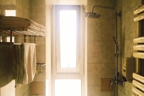 Un bagno con doccia, portasciugamani e una finestra che lascia entrare la luce naturale.