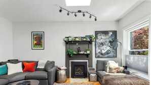 Un salon moderne avec une cheminée, un ensemble de canapés, une table basse et une grande fenêtre donnant sur un beau paysage.