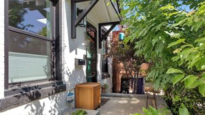 Une maison dotée d’un porche abrité, d’un jardinière en bois et d’un petit espace jardin.