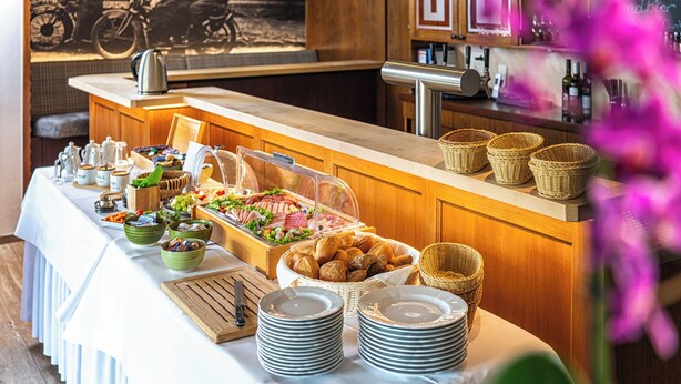 A buffet setup with various food items, baskets, and plates on a table. - Hotel Restaurant Zur Post (Holdorf)