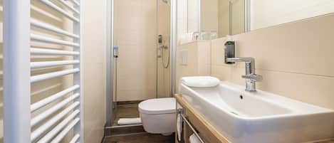 A modern bathroom with a shower, toilet, and sink.