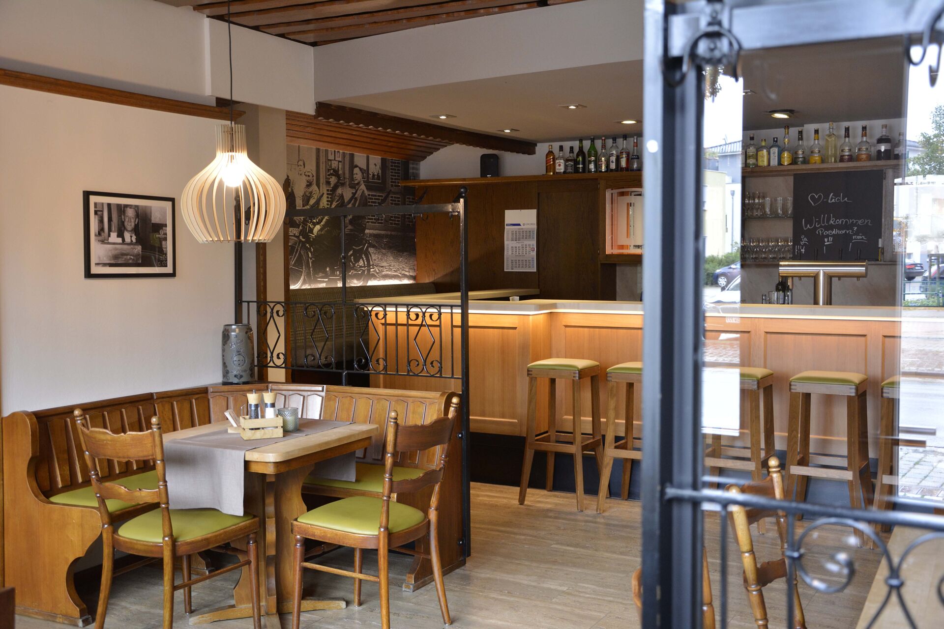 A cozy cafe with wooden furniture, a bar area, and a chalkboard menu.