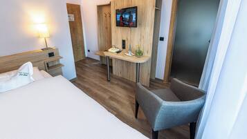 Ein Hotelzimmer mit Bett, Schreibtisch mit Stuhl, Fernseher und Lampe.