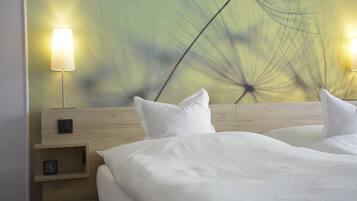 Een hotelkamer met een houten hoofdeinde, twee nachtkastjes met lampen, een klok en een muur met een leeuwenwitje patroon.