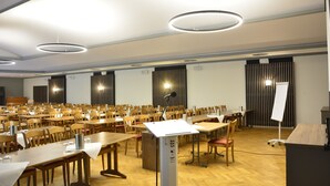 A conference room with multiple tables and chairs, a podium, and a whiteboard. - Hotel Restaurant Zur Post (Holdorf)