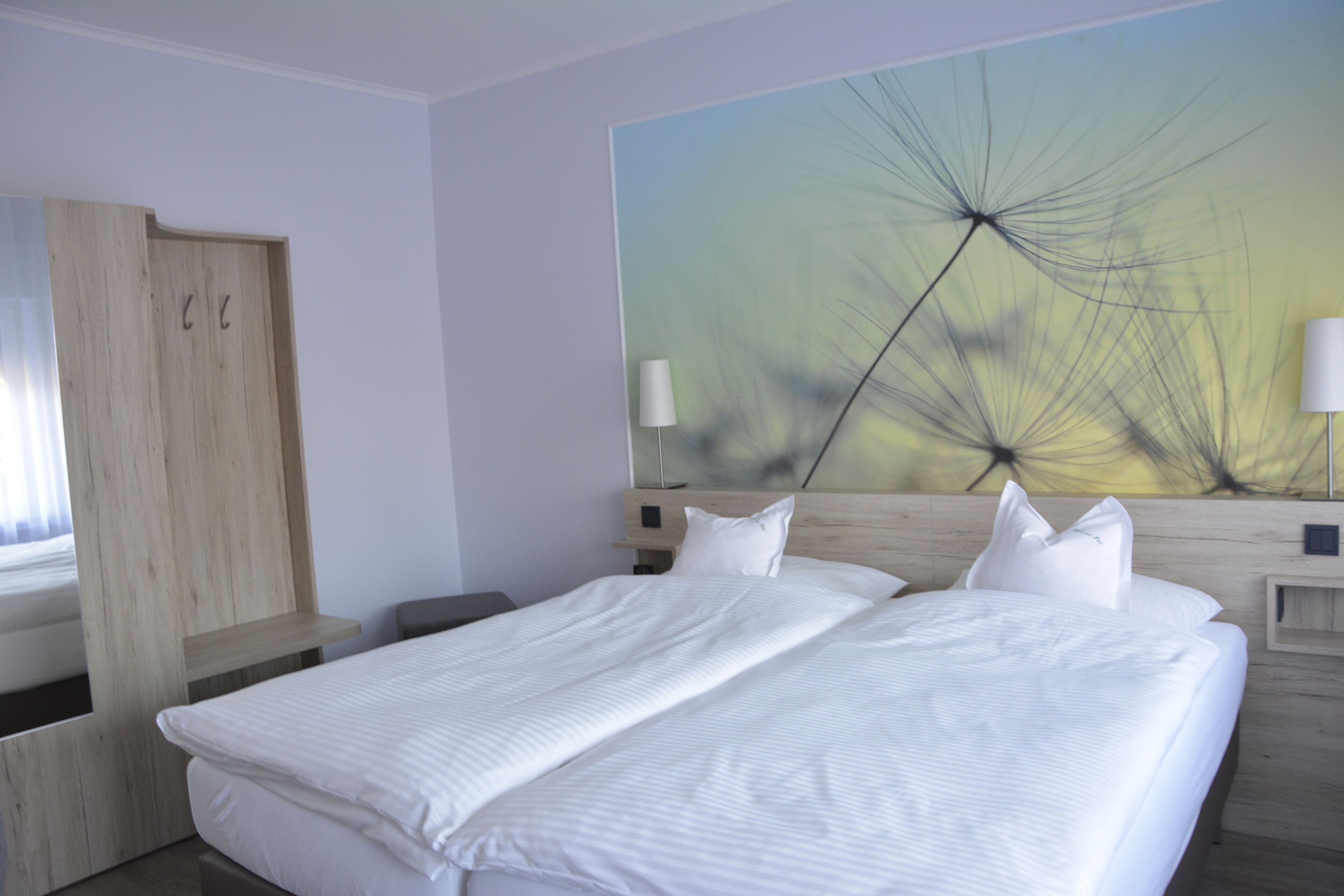 Quarto de hotel moderno com uma cama grande, um guarda-roupa de madeira e uma obra de arte na parede.