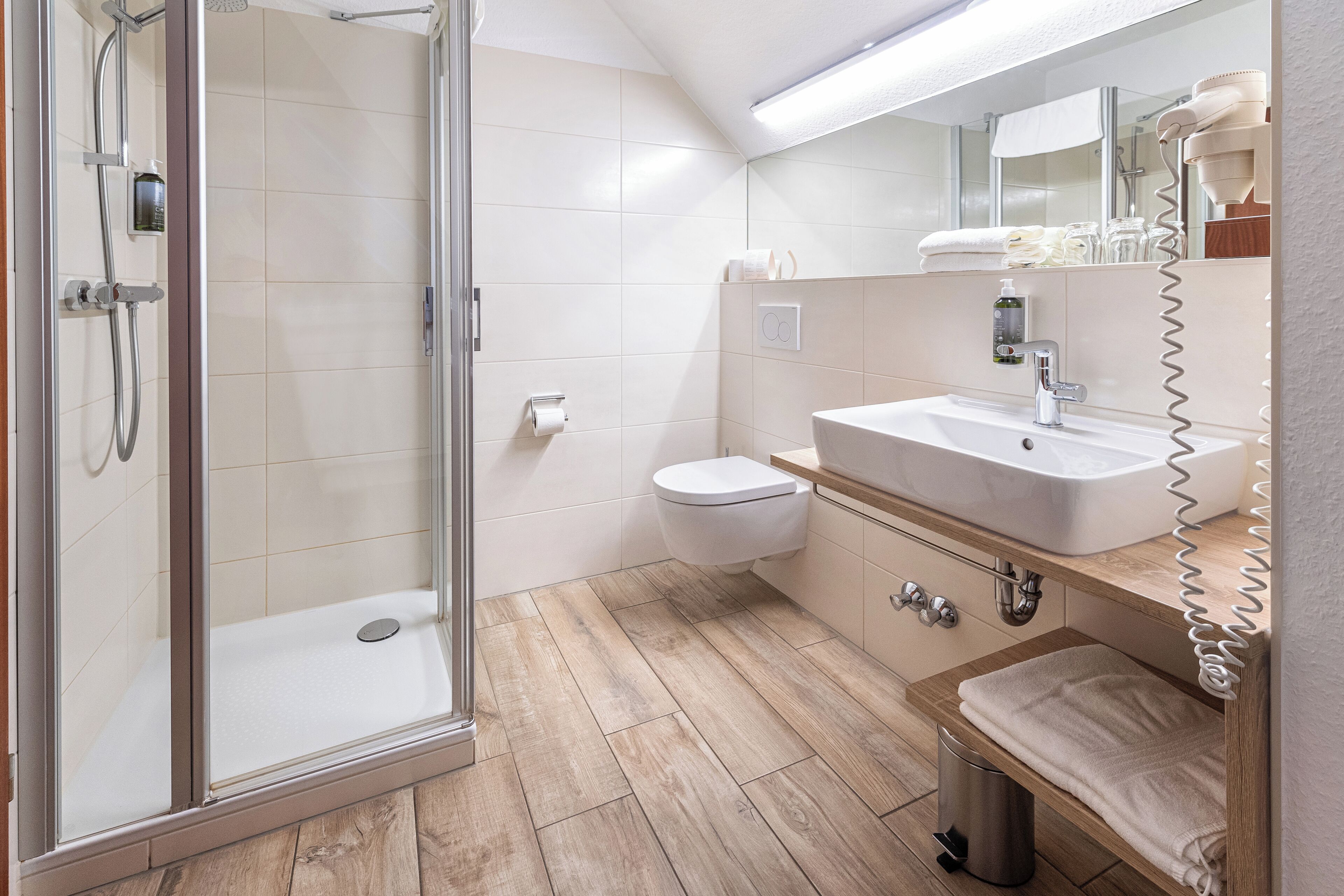 Un baño moderno con cabina de ducha de vidrio, inodoro, lavabo con espejo y toallero.