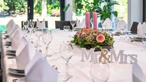 A table set for a wedding reception with white tablecloths, candles, and a floral centerpiece. - Hotel Restaurant Zur Post (Holdorf)