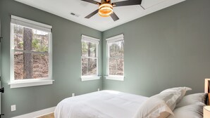 A bedroom with a bed, white bedding, a ceiling fan, and windows with a view of trees. - 6 Mi to Chattanooga: Home w/ Balcony & Dtwn Views! (Rossville)