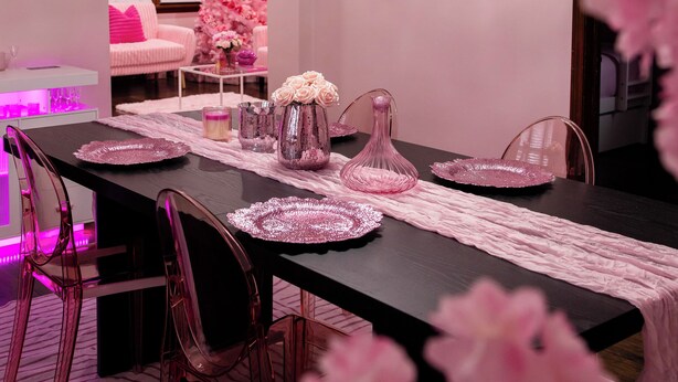 En matplats med ett långt bord, rosa stolar och en kristallkrona.