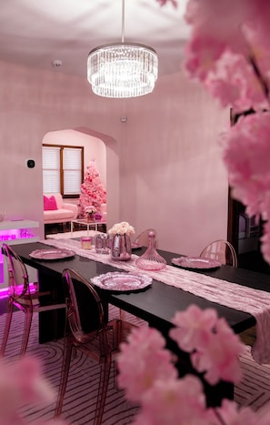 A dining area with a long table, pink chairs, and a chandelier. - Pink Diamond Rental in Bayview area Milwaukee with WiFi, AC for pink lovers (Milwaukee)