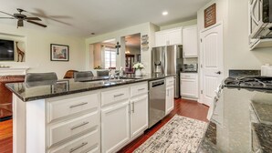 Una cocina moderna con gabinetes blancos, electrodomésticos de acero inoxidable y encimera de granito.