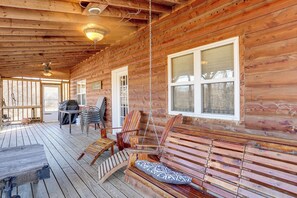 Eine Holzterrasse mit Schaukelstuhl, Tisch und Grillplatz.