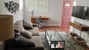 A living room with a sofa, coffee table, and a TV on a stand.