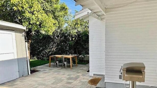 A patio area with a stone floor, a wooden table with chairs, and a mailbox.