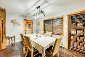 Un comedor con una mesa de madera, sillas y una lámpara colgante.
