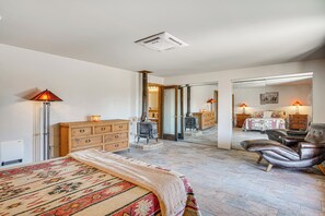 Un dormitorio con cama, cómoda, silla y un espejo que refleja la habitación.