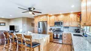 Una cocina moderna con armarios de madera, electrodomésticos de acero inoxidable y encimera de granito.