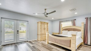 Une chambre à coucher avec un lit, un ventilateur de plafond, une armoire et une porte donnant sur l’extérieur.