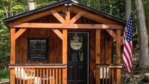 A wooden cabin with a black door, a welcome sign, and an American flag. - Close to Trails: Studio w/ Water Views (Wurtsboro)